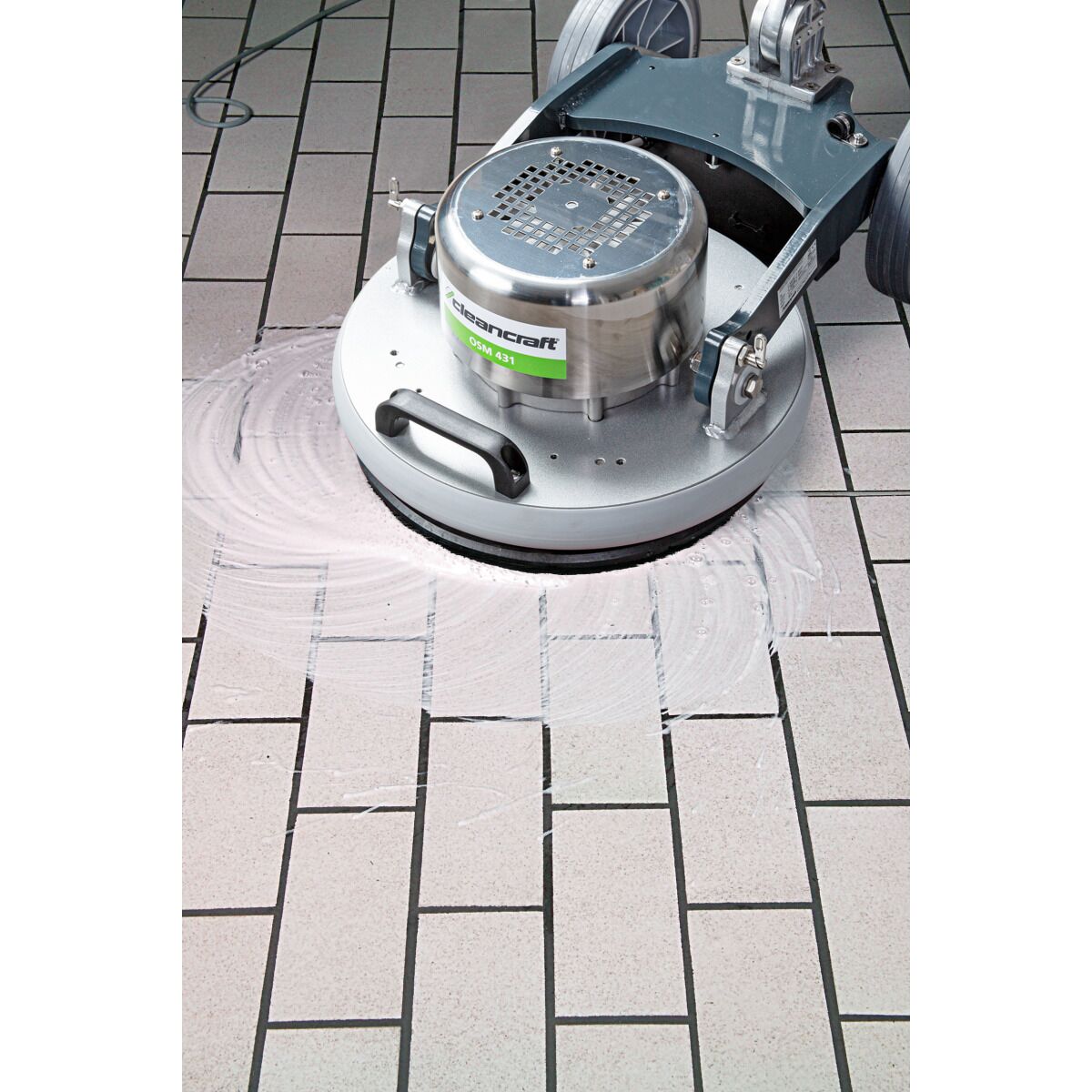 Bodenreinigungsmaschine mit Schaumresten auf hellen Fliesen, zeigt Reinigungsvorgang.