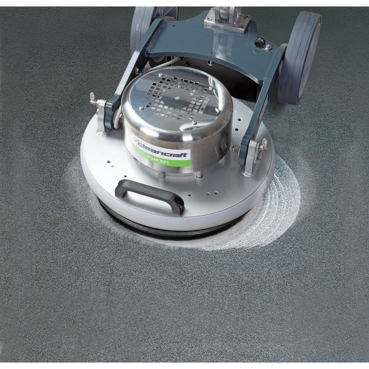 Bodenreinigungsmaschine poliert strukturierten grauen Boden, heller Kreis durch Polierbewegung erkennbar.