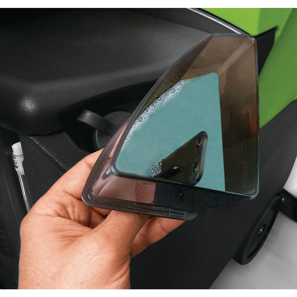 Hand hält transparenten Wassertankdeckel mit sichtbaren Seifenblasen.