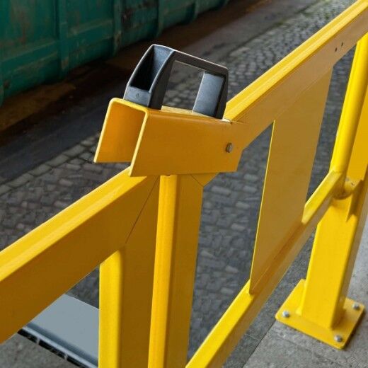 Gelbes Schutzgeländer mit Verriegelung und schwarzem Griff im Außenbereich auf Rampe montiert.