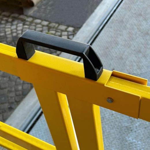 Gelbes Tor mit schwarzem Griff, montiert auf Rampe, daneben Pflaster- und Metallboden sichtbar.