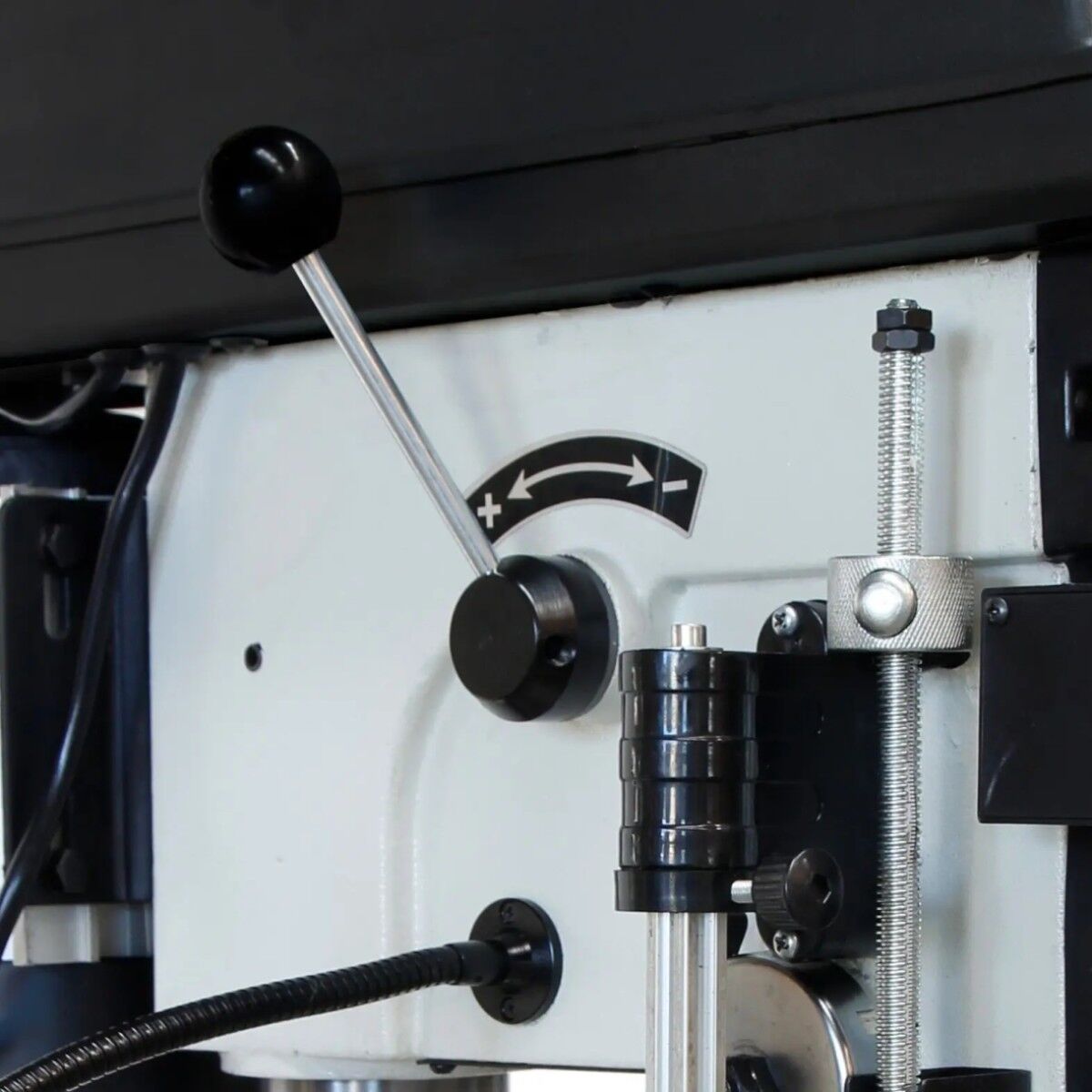 Nahaufnahme des Verstellhebels der ELMAG Tischbohrmaschine KBM 16 T VARIO mit Plus-Minus-Markierung, Gewindestange und Halterung.