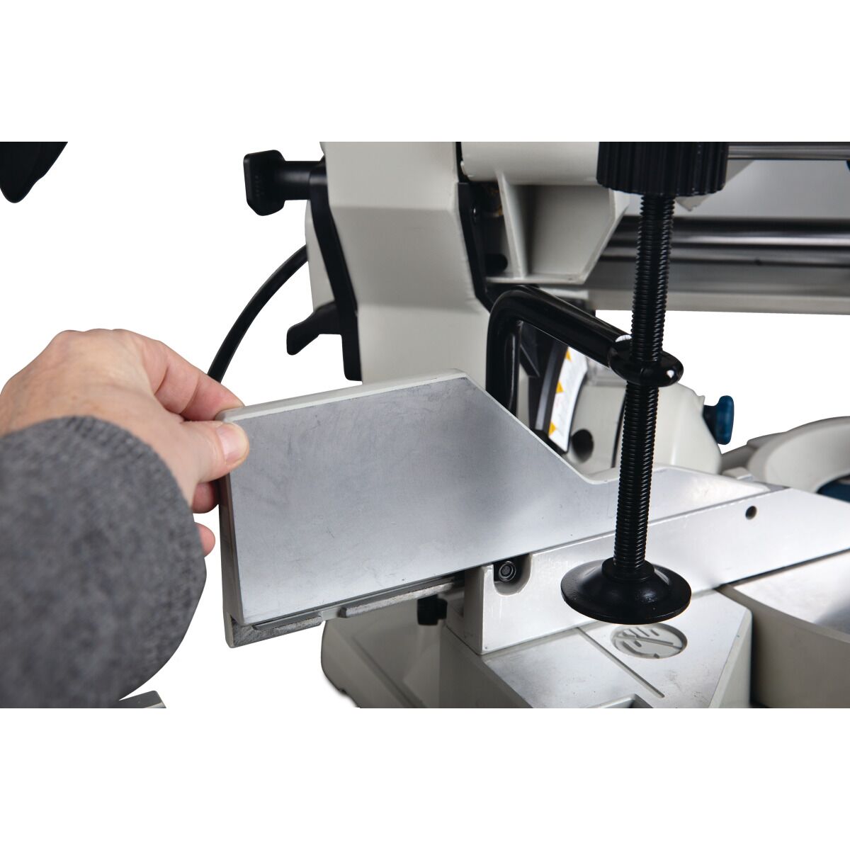 Hand setzt Metallanschlag an der Gehrungssäge ein, Detailaufnahme.