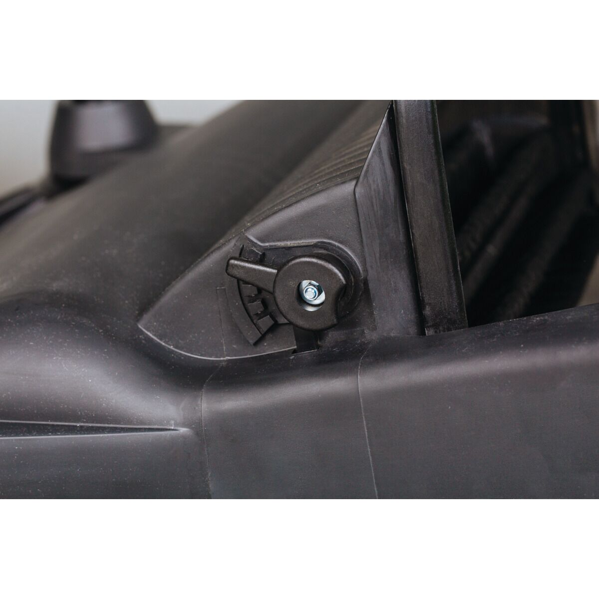 Detailaufnahme einer seitlichen Einstellungsschraube am Gehäuse der Kehrmaschine.