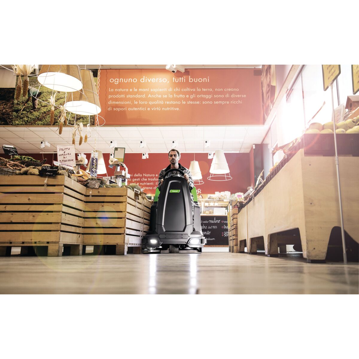 Eine Aufsitz-Scheuersaugmaschine wird in einem Lebensmittelgeschäft zwischen Holzauslagen eingesetzt.