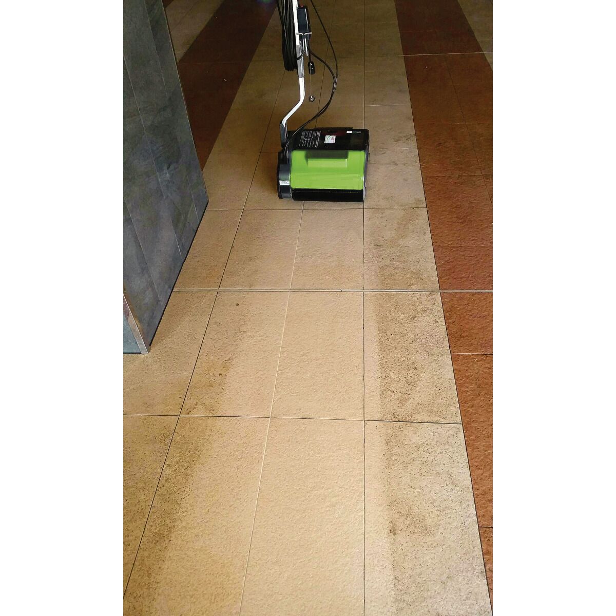 Bodenreinigungsmaschine im Einsatz auf Fliesen, deutlicher Vorher-Nachher-Effekt sichtbar.