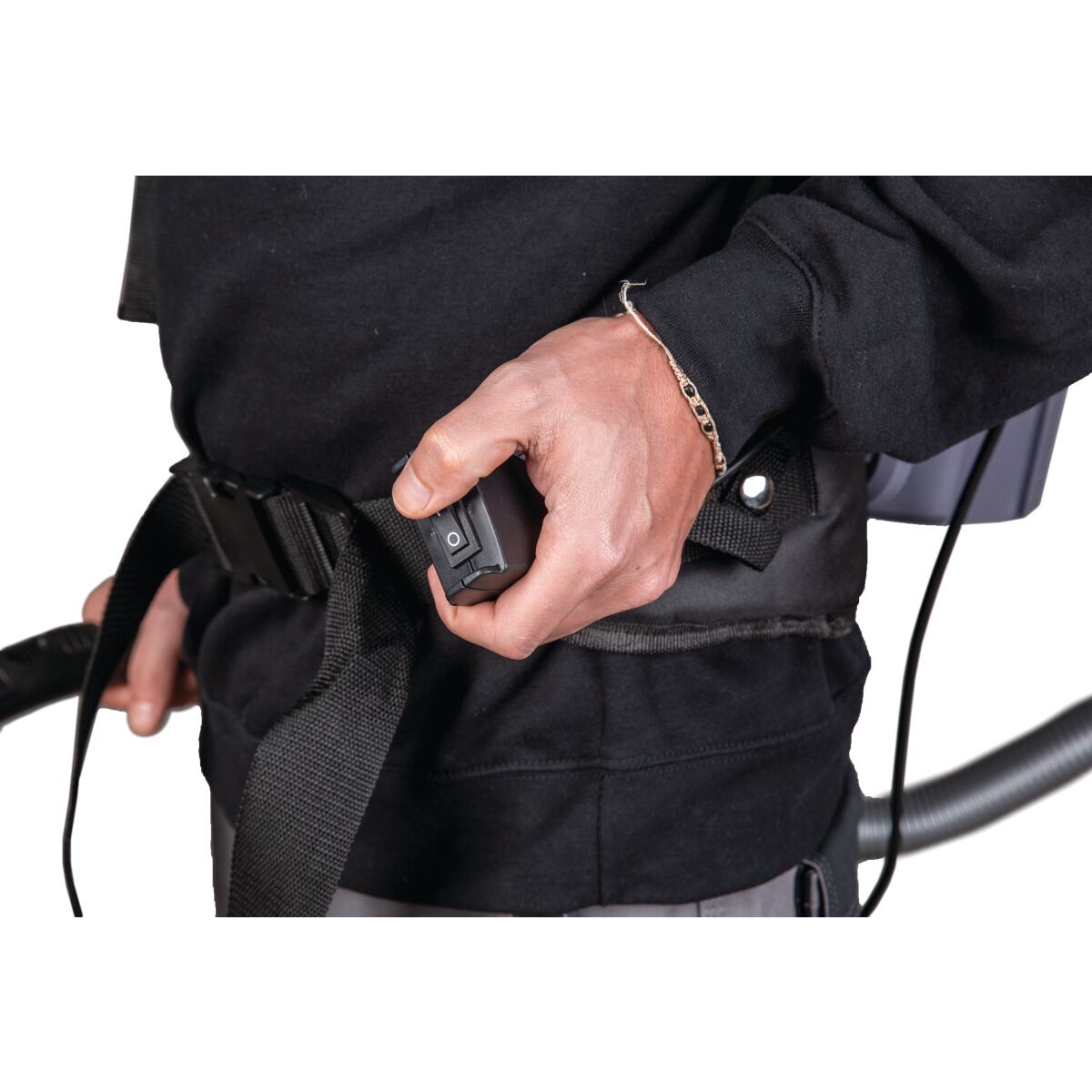 Person mit Rucksackstaubsauger, hält den Schalter am Hüftgurt in der Hand.