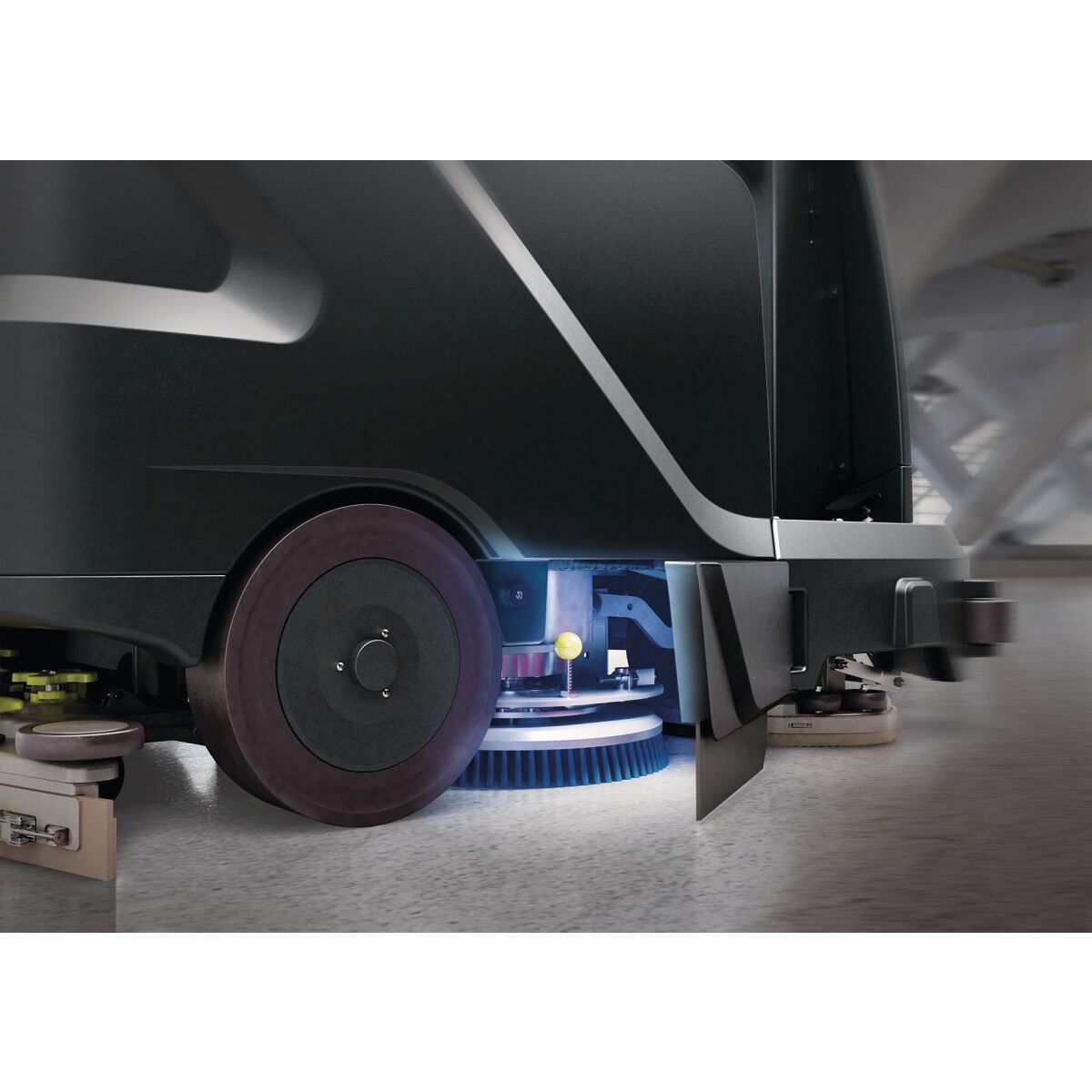 Seitenansicht mit rotierender Bürste unter der Reinigungsmaschine im Betrieb.