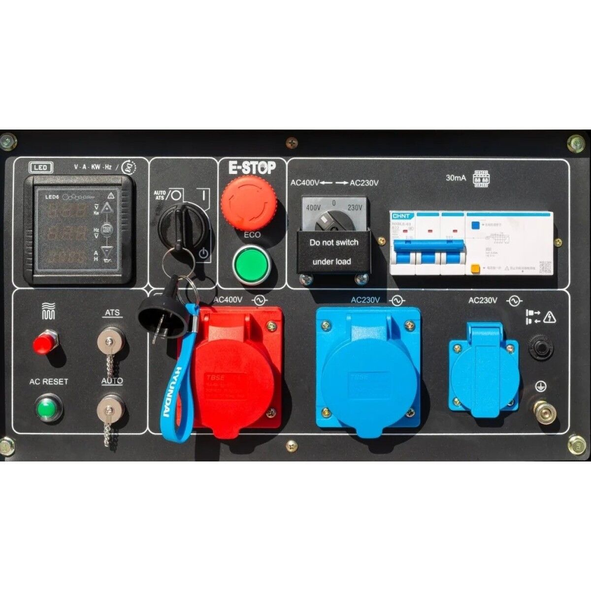 Bedienfeld eines Dieselgenerators mit Not-Aus, Display, Schlüsselschalter, Sicherungen sowie roten und blauen Steckdosen.