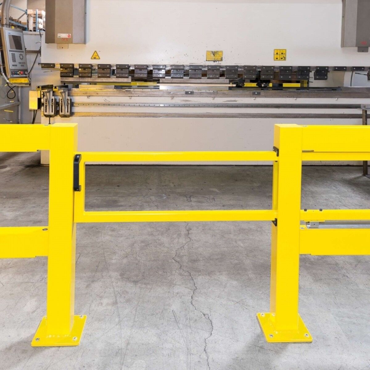 Gelbe Schutzbarriere vor einer Abkantpresse in Werkhalle, mit Schiebetor-Element und schwarzem Griff.