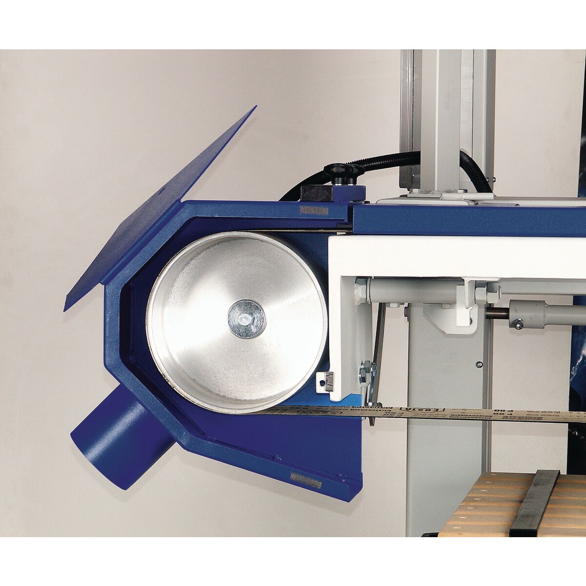 Nahaufnahme der linken Umlenkrolle mit Schleifband, Schutzhaube und Absaugstutzen an der Langbandschleifmaschine.