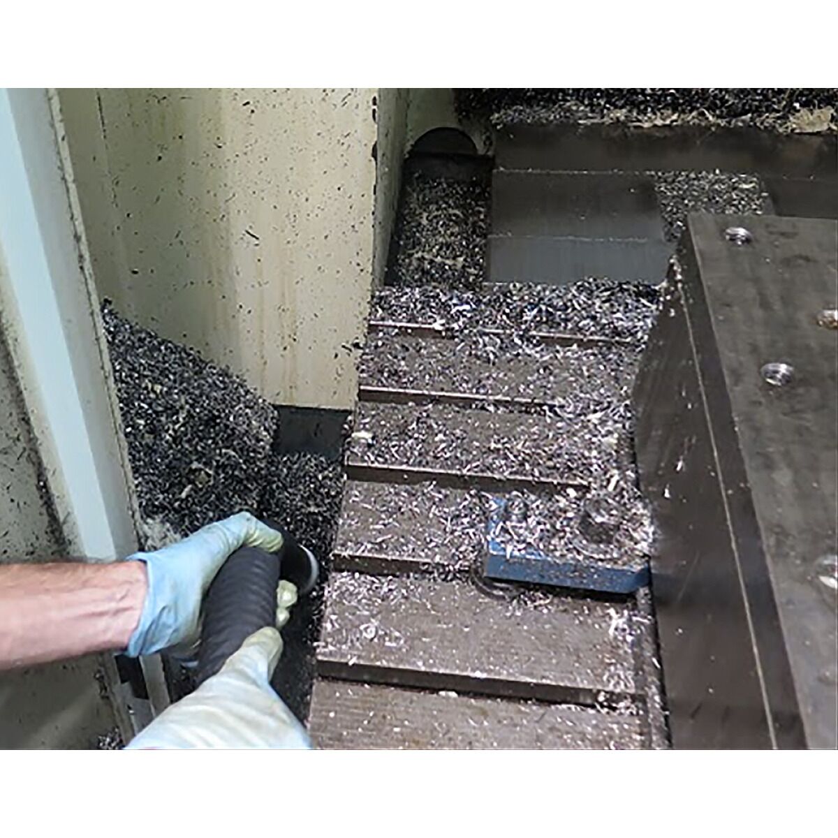 Behälter eines Saugers mit eingesetztem Metallsieb, gefüllt mit Metallspänen.