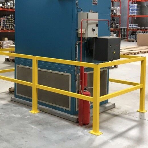 Gelbes Schutzgeländer um eine große blaue Maschine in einem Lager, schützt vor direktem Zugang.