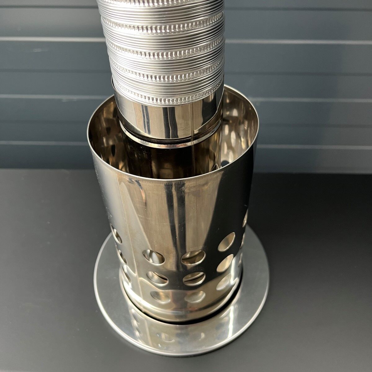 Nahaufnahme eines glänzenden Edelstahl-Abgasrohrs mit gelochtem Mantel.