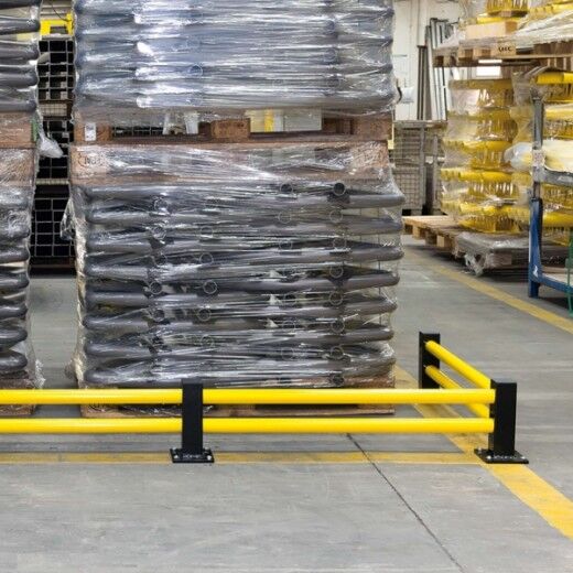 Gelb-schwarze Bodenbarriere schützt gelagerte, folierte Paletten in einer Produktionshalle vor Fahrzeugkollisionen.