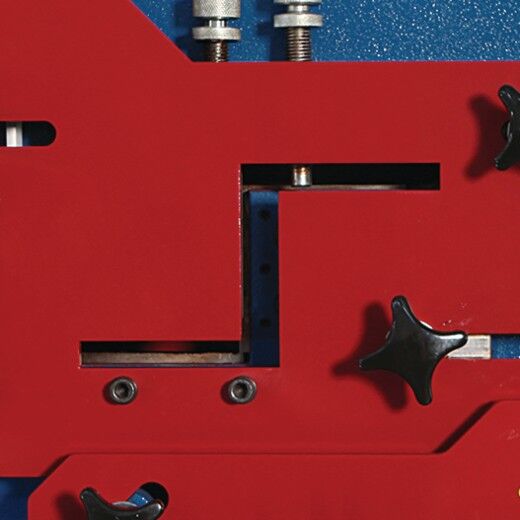 Nahaufnahme der oberen Werkzeugaufnahme mit Einstellschrauben und Führungsschlitzen.