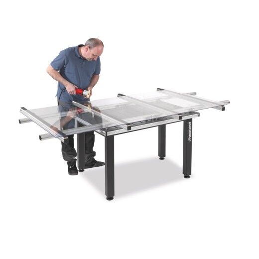Mann arbeitet mit Handwerkzeug an großem Arbeitstisch mit transparenter Auflage und Metallgestell.