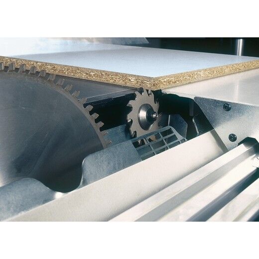 Nahaufnahme einer Kreissäge mit Vorritzsägeblatt, das eine Spanplatte von unten einschneidet.